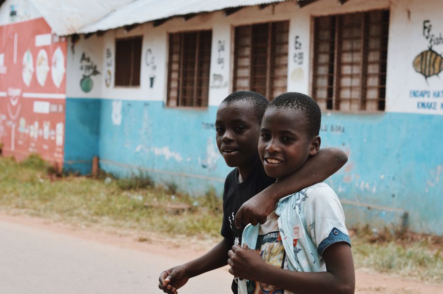Two children smiling outside a school