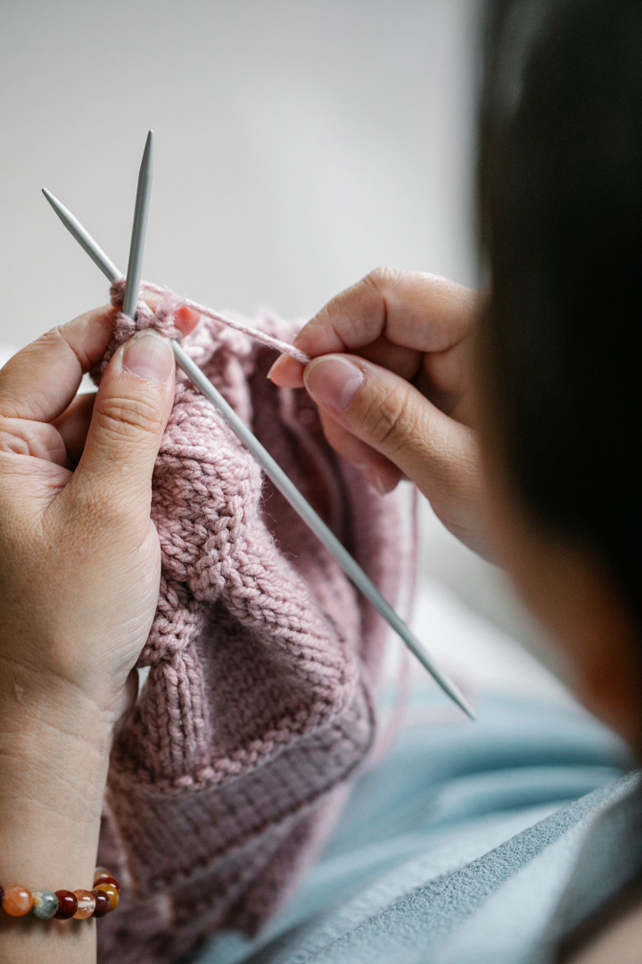 Hands knitting a soft pink shawl