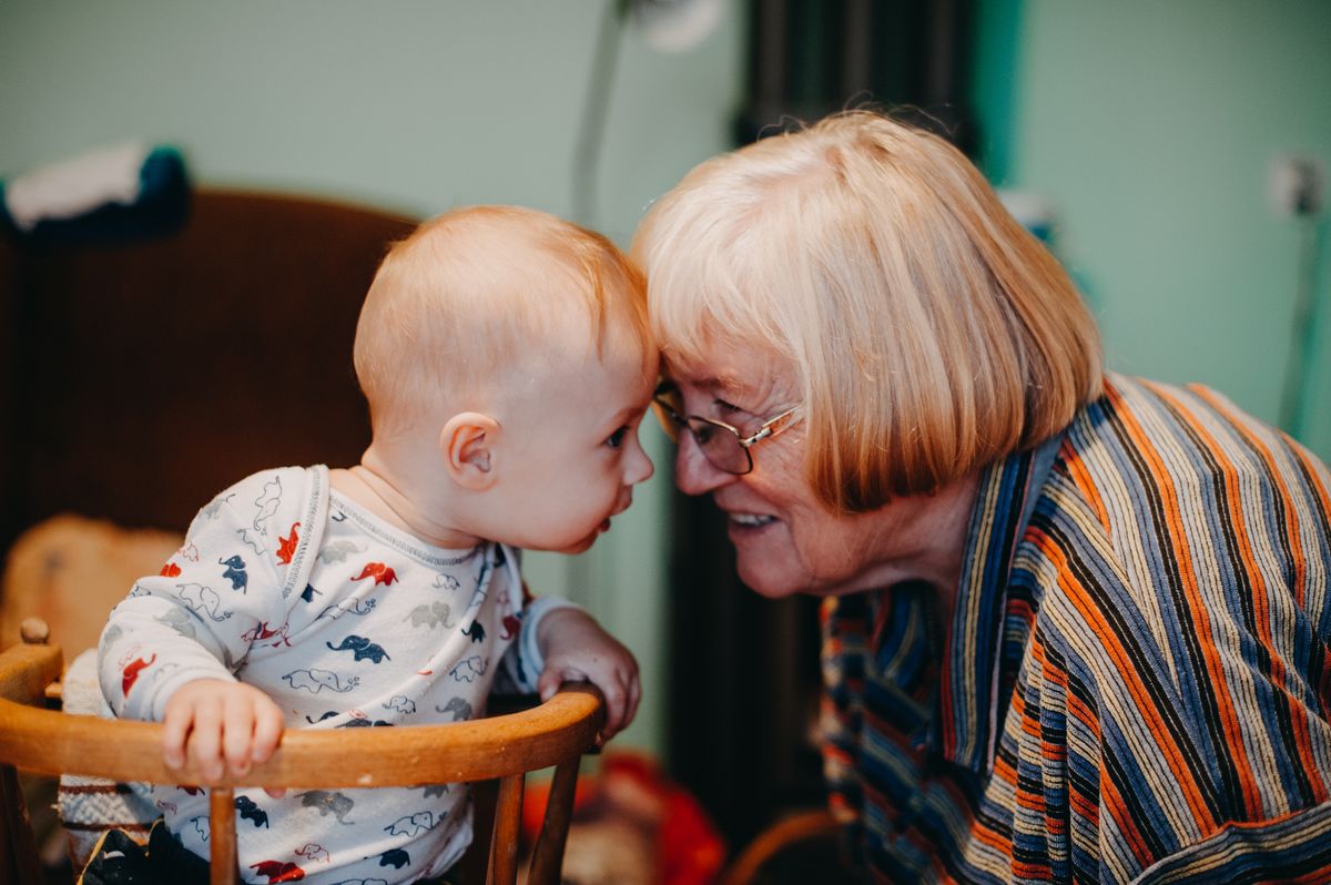 A grandmother holding a smiling baby close